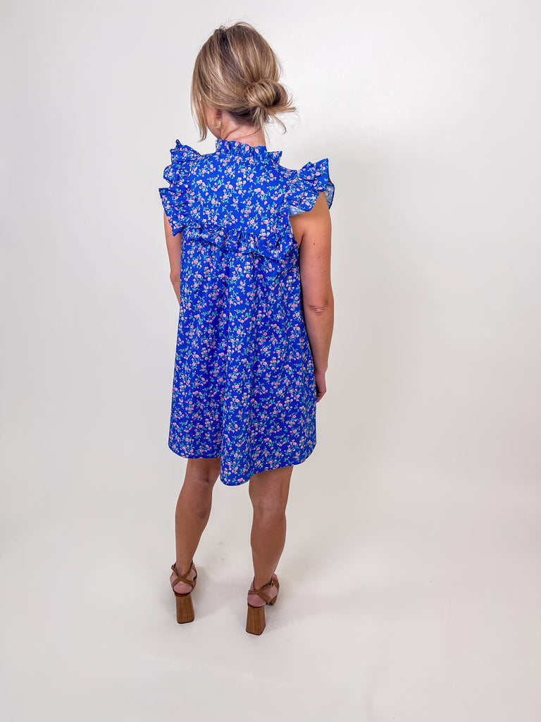 Woman wearing a blue floral babydoll dress with ruffle sleeves and a keyhole neckline.