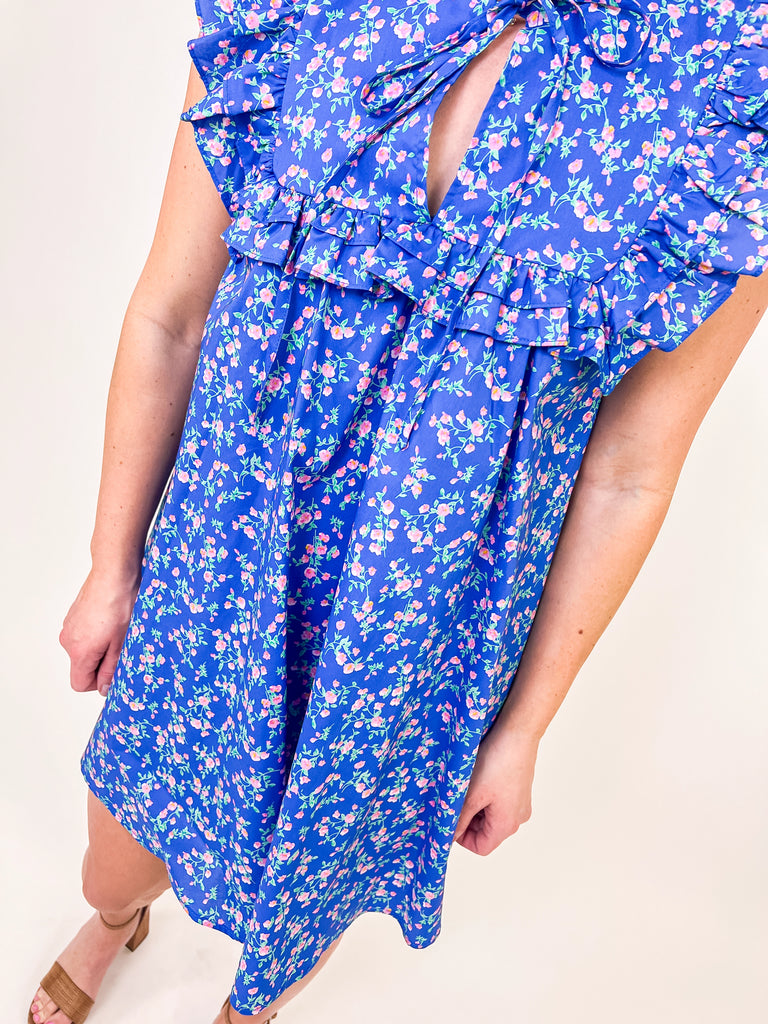 Woman wearing a blue floral babydoll dress with ruffle sleeves and a keyhole neckline.