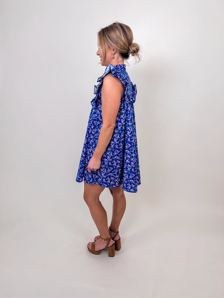 Woman wearing a blue floral babydoll dress with ruffle sleeves and a keyhole neckline.
