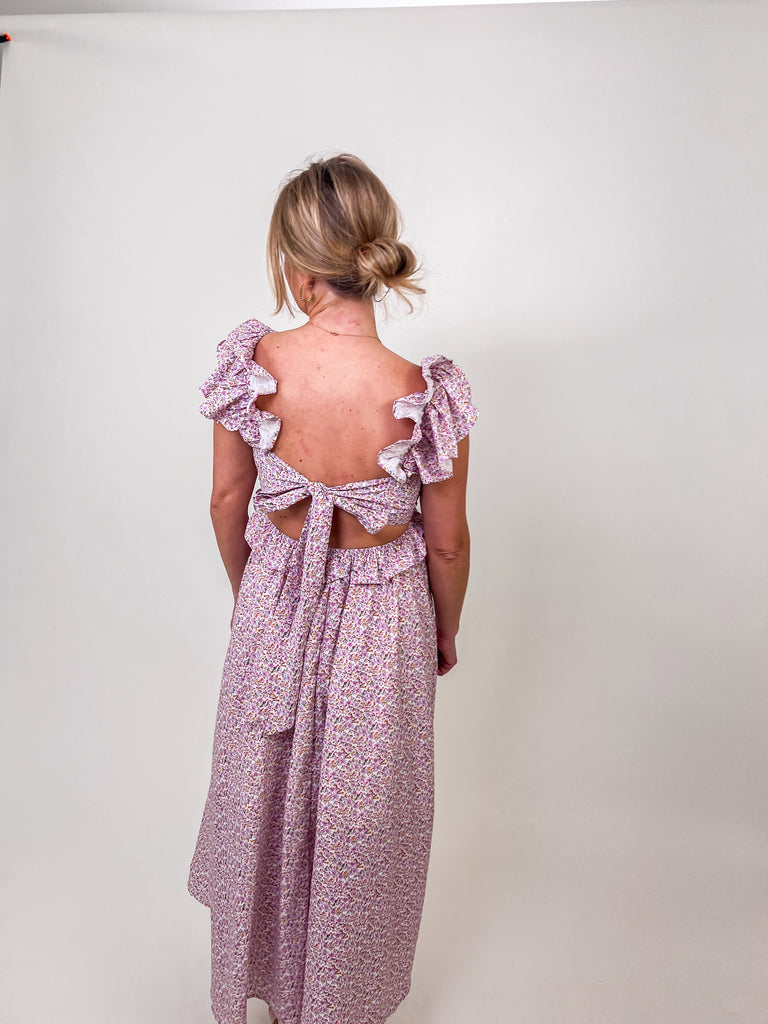 Woman wearing a floral ruffle maxi dress with an open tie-back and V-neckline.