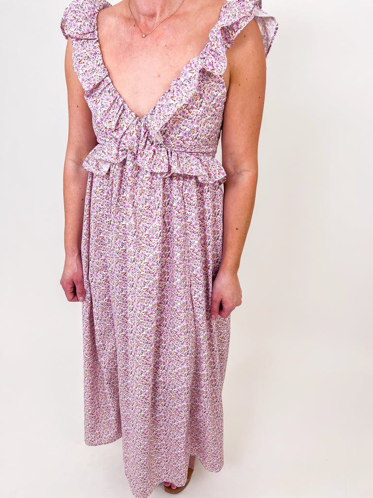 Woman wearing a floral ruffle maxi dress with an open tie-back and V-neckline.