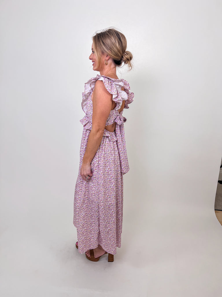 Woman wearing a floral ruffle maxi dress with an open tie-back and V-neckline.