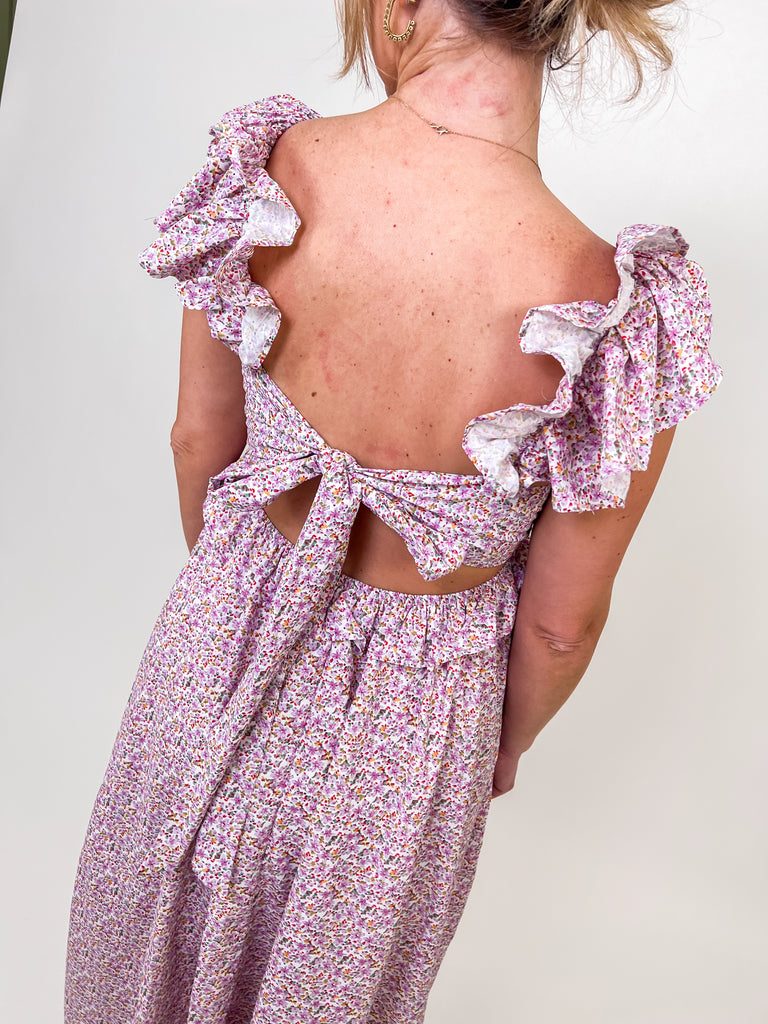 Woman wearing a floral ruffle maxi dress with an open tie-back and V-neckline.