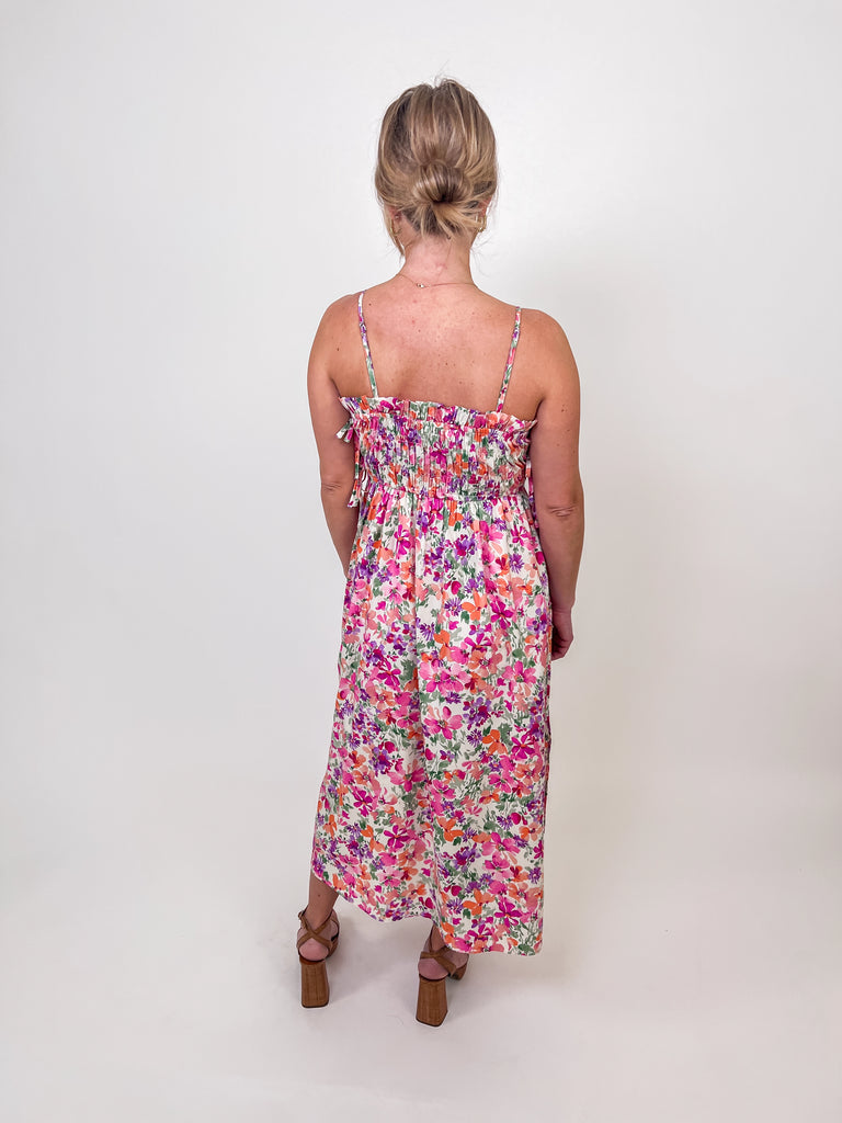Woman wearing a floral smocked midi dress with tie straps and a flowy silhouette.