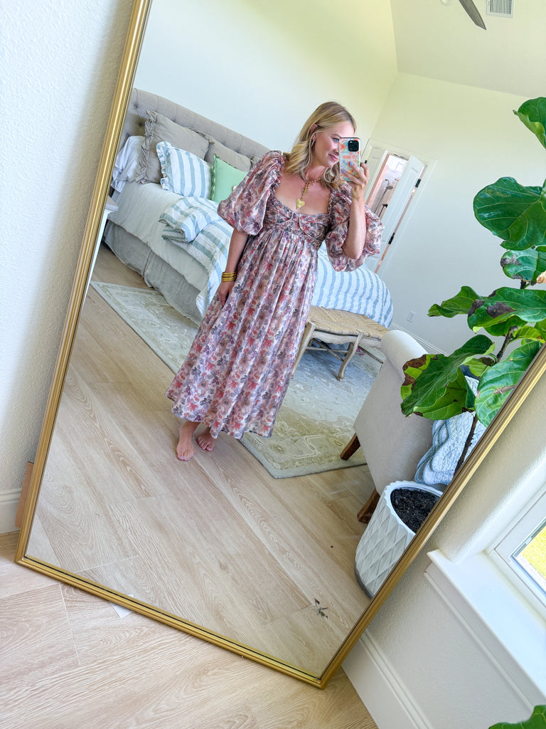 Woman wearing a watercolor floral maxi dress with puff sleeves and smocked bodice