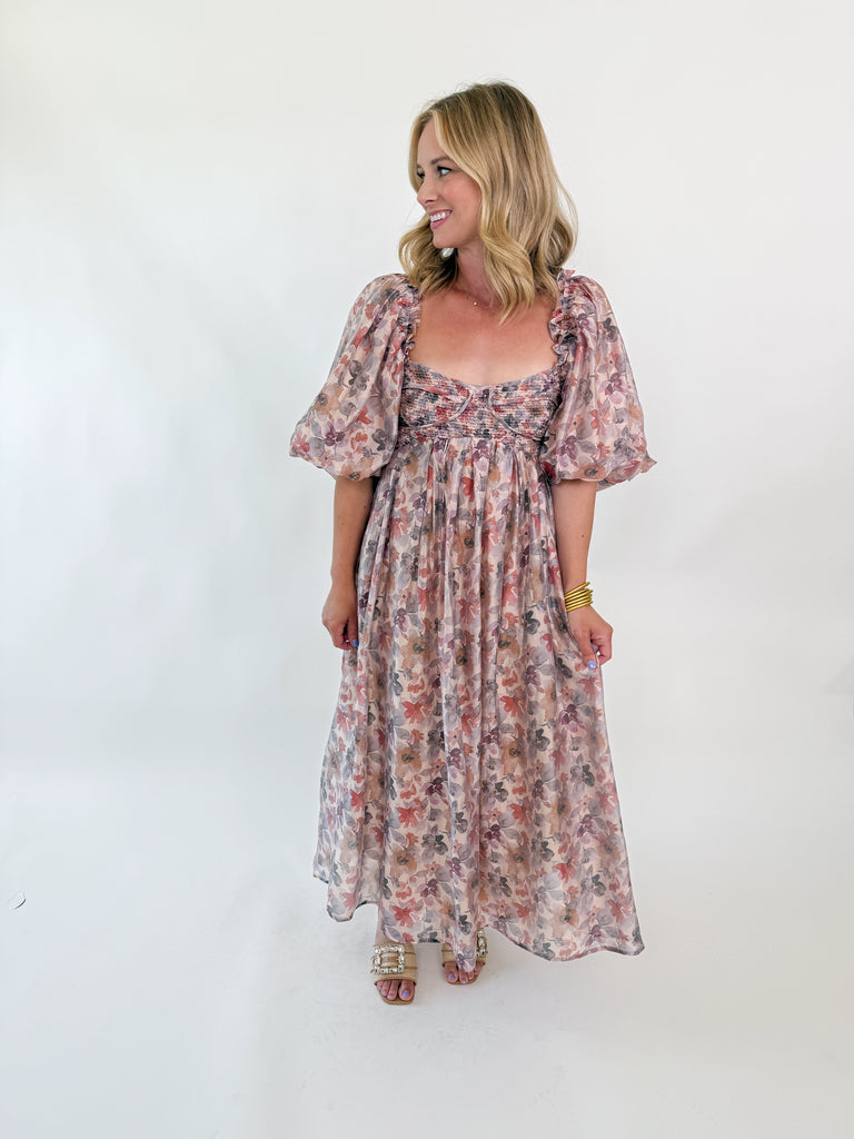 Woman wearing a watercolor floral maxi dress with puff sleeves and smocked bodice