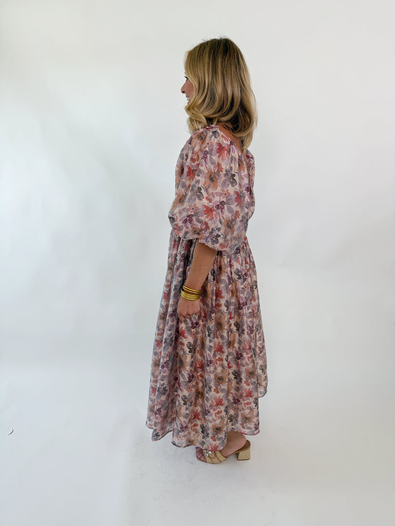  Woman wearing a watercolor floral maxi dress with puff sleeves and smocked bodice