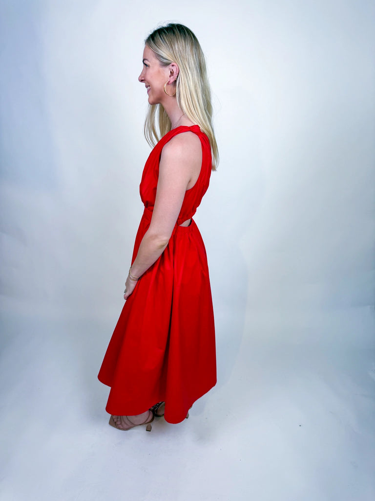 Woman wearing the Scarlet Spice Dress, a red one-shoulder midi with knotted strap and waist cutout.