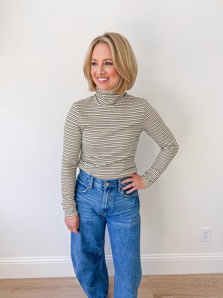 Women’s striped turtleneck long-sleeve top, paired with high-waisted denim jeans, available for sale at an online women’s boutique