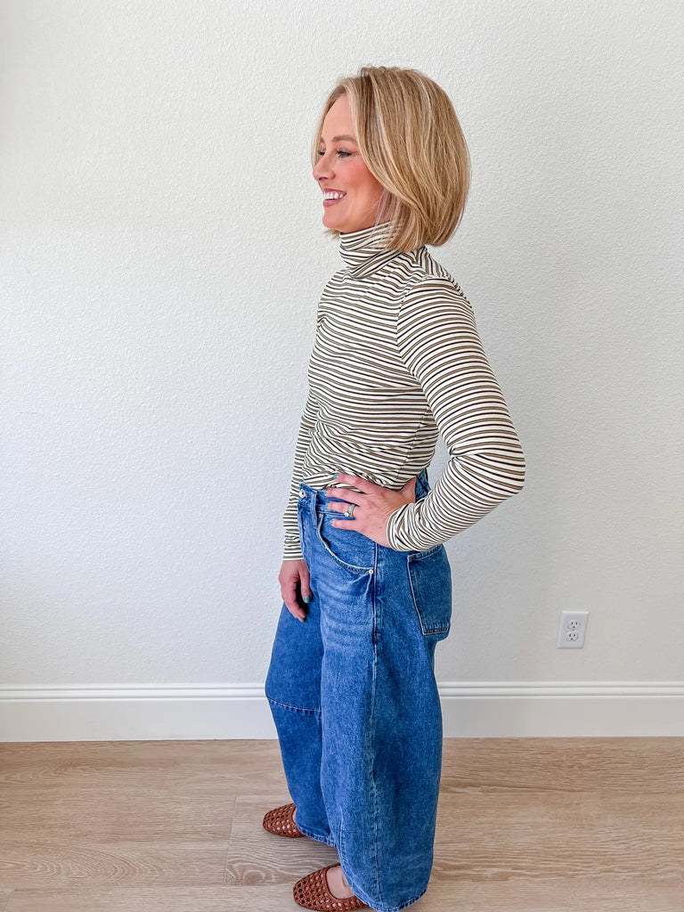 Women’s striped turtleneck long-sleeve top, paired with high-waisted denim jeans, available for sale at an online women’s boutique