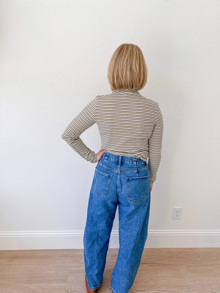Women’s striped turtleneck long-sleeve top, paired with high-waisted denim jeans, available for sale at an online women’s boutique