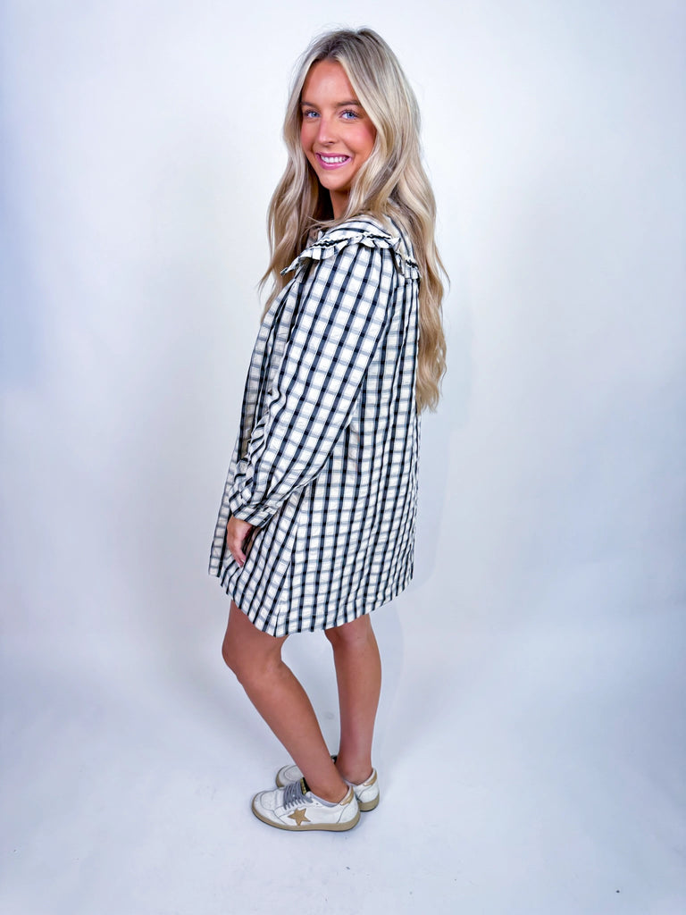 Woman wearing Autumn Stroll Dress in white with black and mustard with dark green, styled for fall