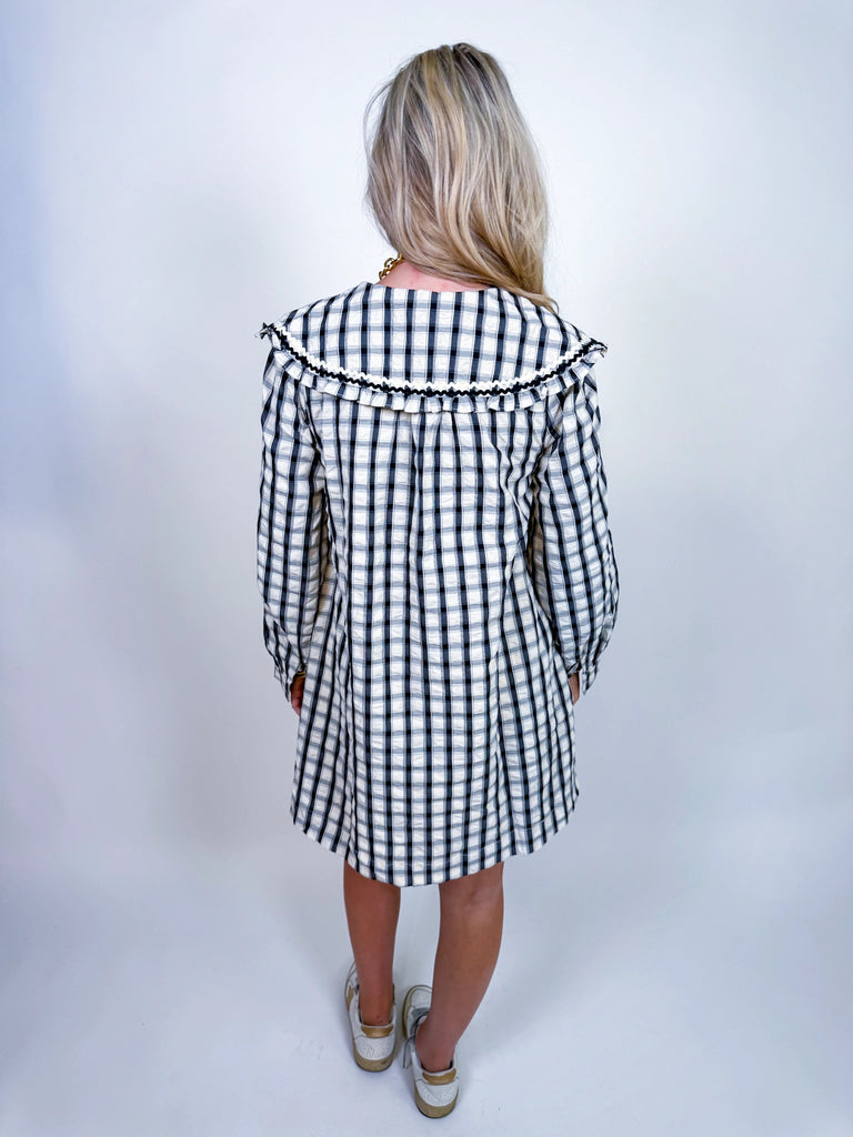 Woman wearing Autumn Stroll Dress in white with black and mustard with dark green, styled for fall