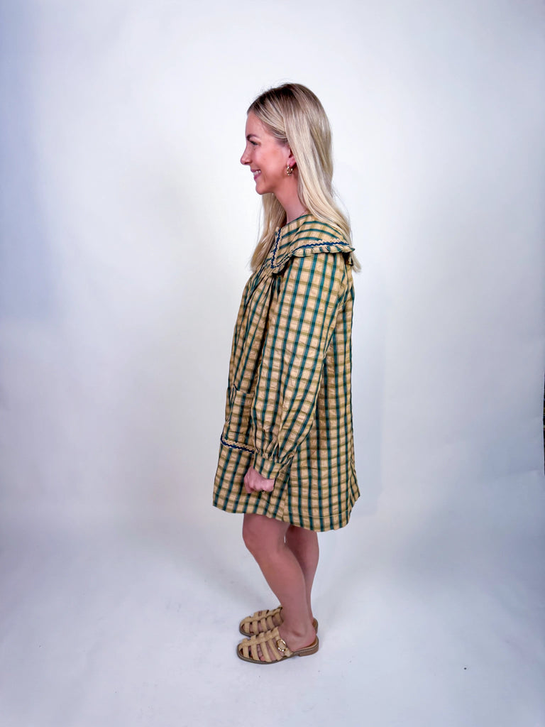 Woman wearing Autumn Stroll Dress in white with black and mustard with dark green, styled for fall