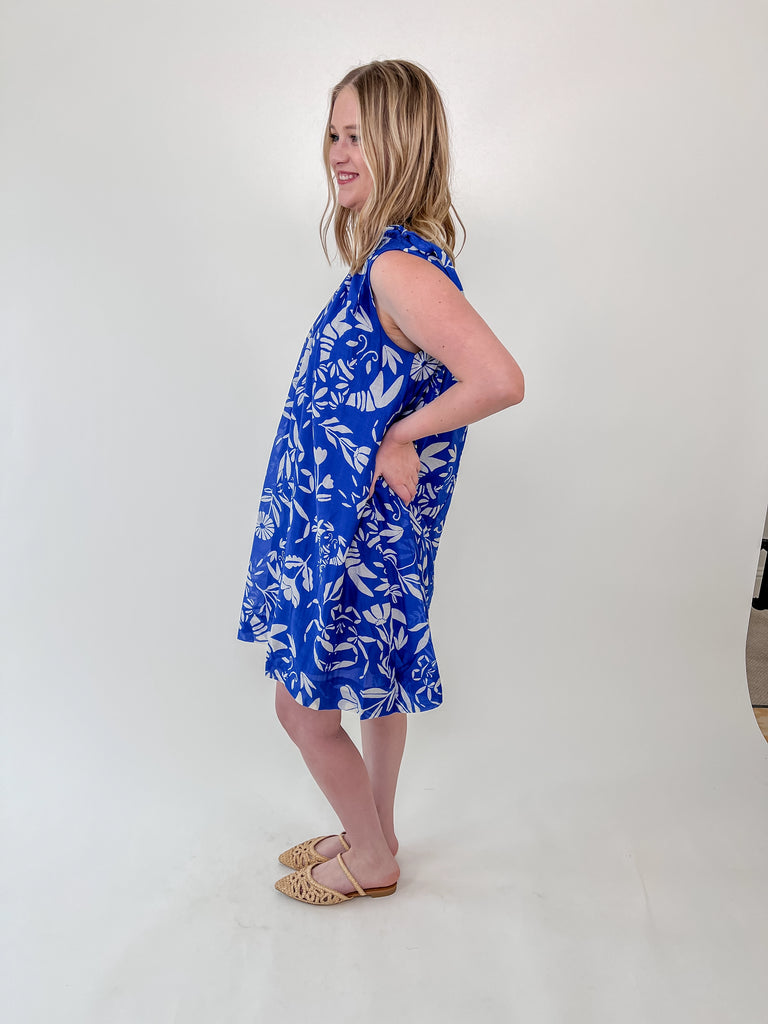 Woman wearing a blue shift dress with white lobster and crab print and tie-shoulder straps