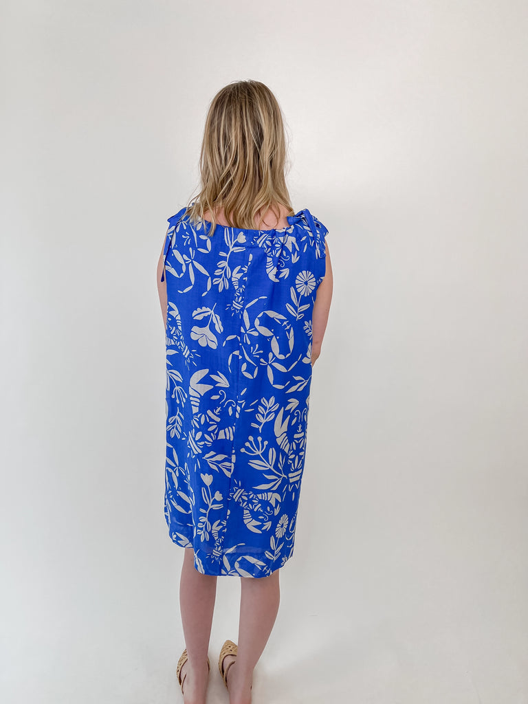 Woman wearing a blue shift dress with white lobster and crab print and tie-shoulder straps