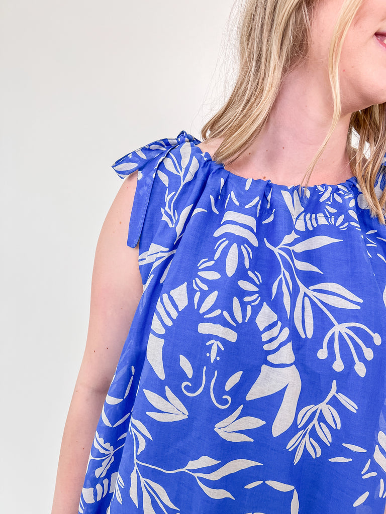 Woman wearing a blue shift dress with white lobster and crab print and tie-shoulder straps