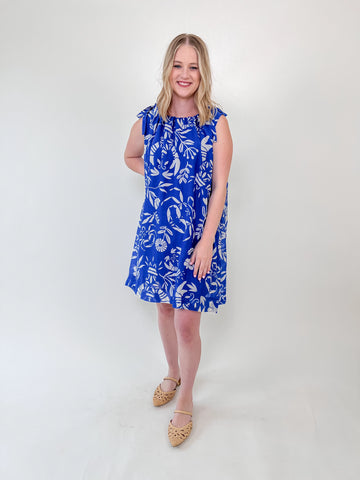 Woman wearing a blue shift dress with white lobster and crab print and tie-shoulder straps
