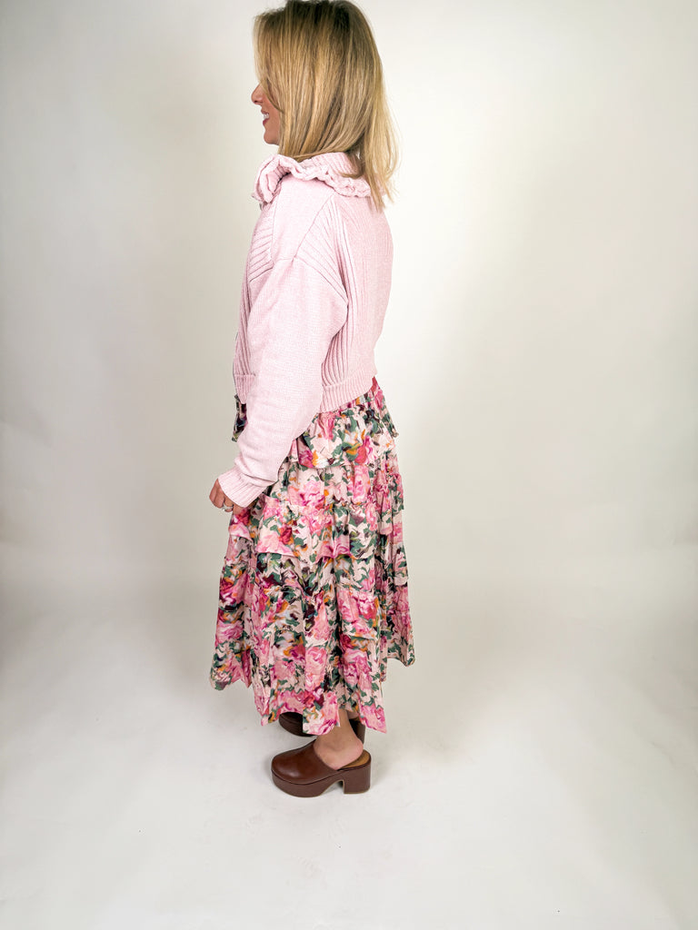 Woman wearing blush pink ruffle zip jacket with ribbed knit texture and feminine collar detail