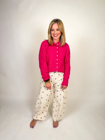 Woman wearing a vibrant hot pink button-down knit sweater with long sleeves and a slightly cropped hem