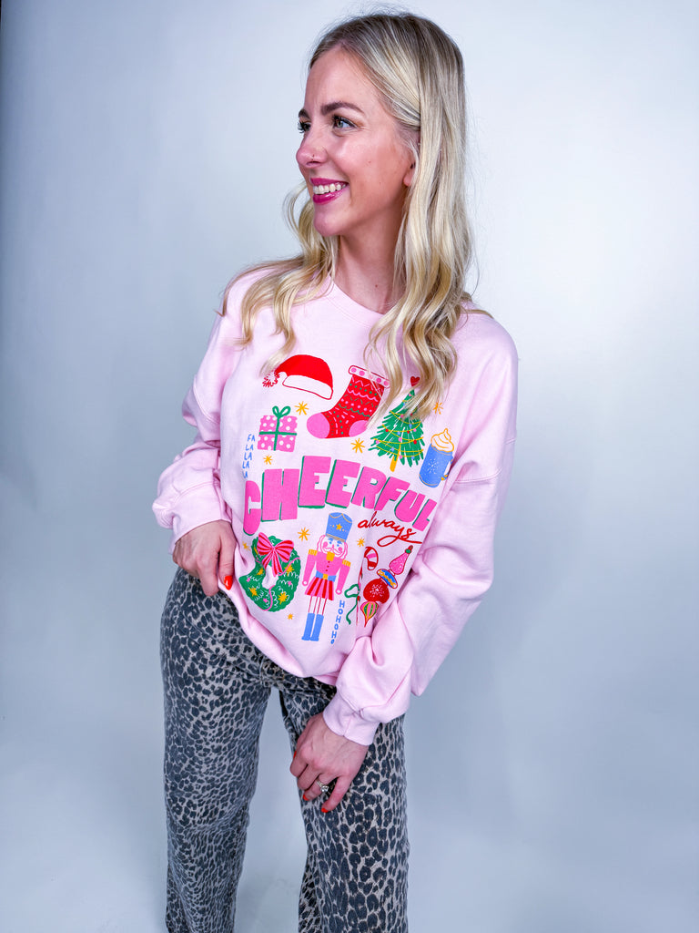 Woman wearing pink Cheerful Always sweatshirt with festive Christmas icons and lettering