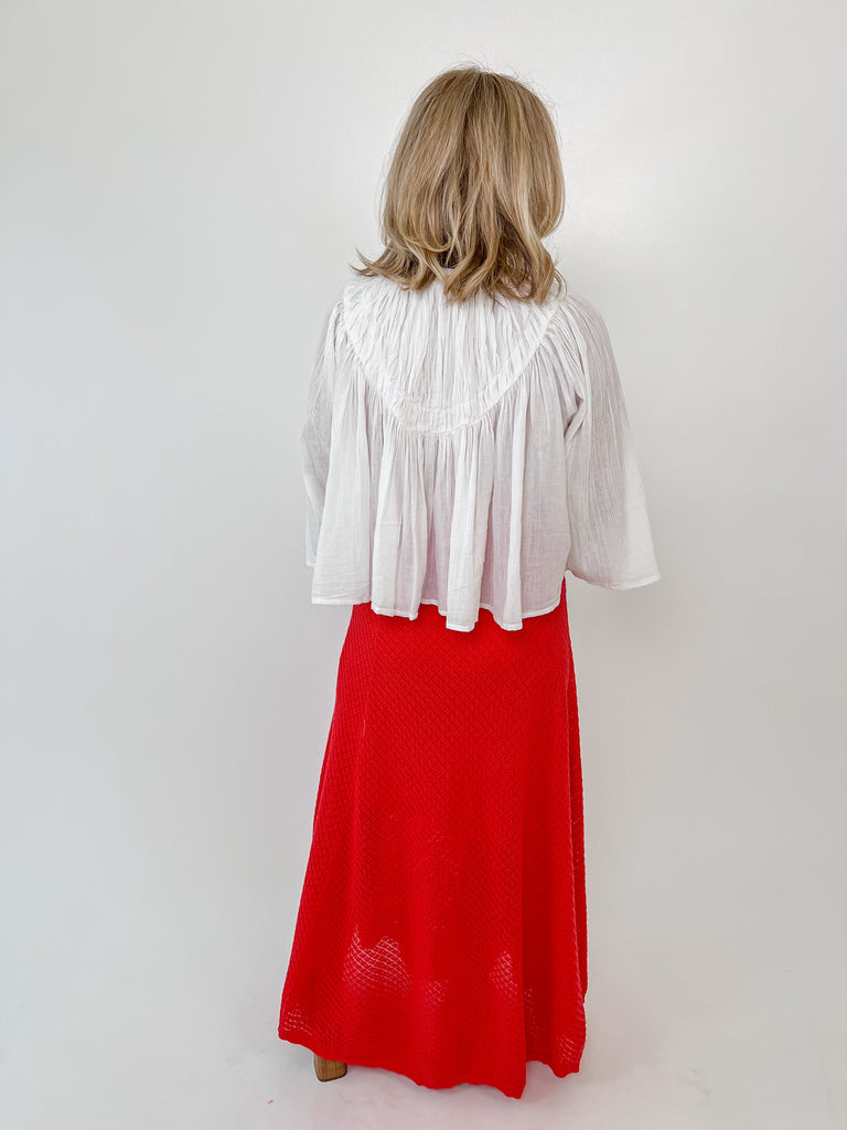 Woman wearing a red textured knit midi skirt with a drawstring waist and flowy fit