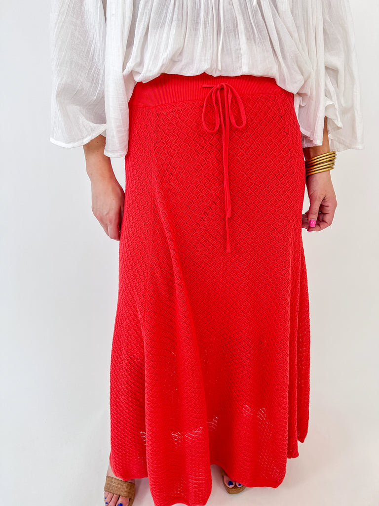 Woman wearing a red textured knit midi skirt with a drawstring waist and flowy fit