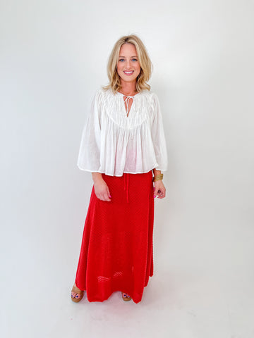 Woman wearing a red textured knit midi skirt with a drawstring waist and flowy fit