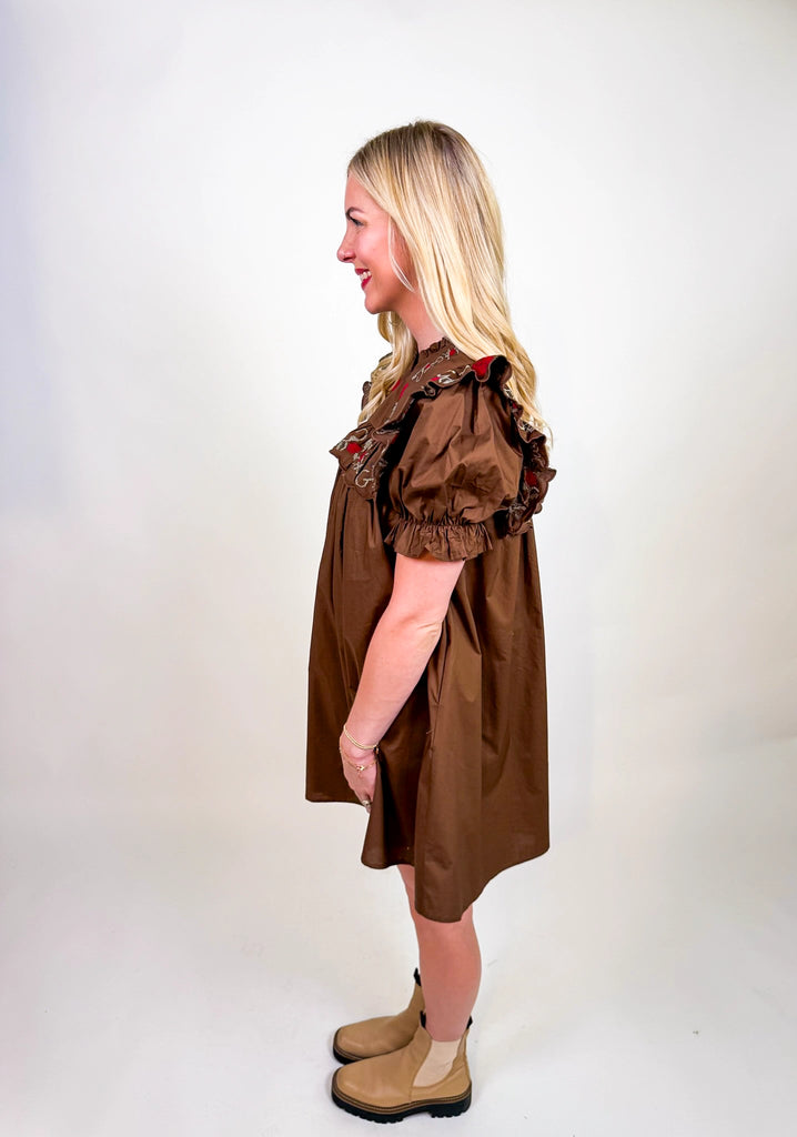 Woman wearing Chestnut Bloom Dress in brown with red floral embroidery and ruffled sleeves