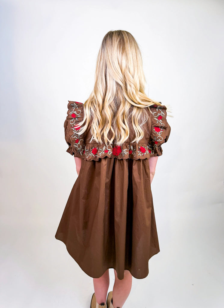 Woman wearing Chestnut Bloom Dress in brown with red floral embroidery and ruffled sleeves