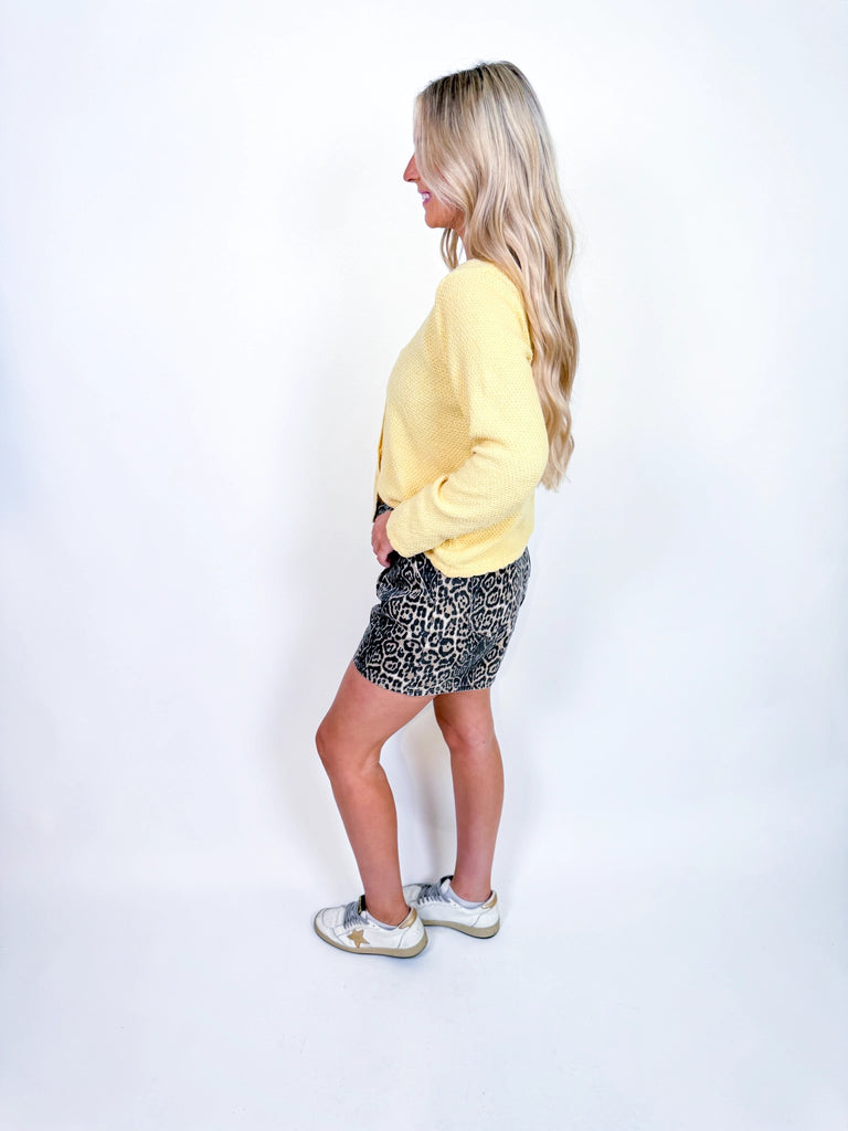 Woman wearing textured knit button-front cardigan in butter yellow and cornflower blue