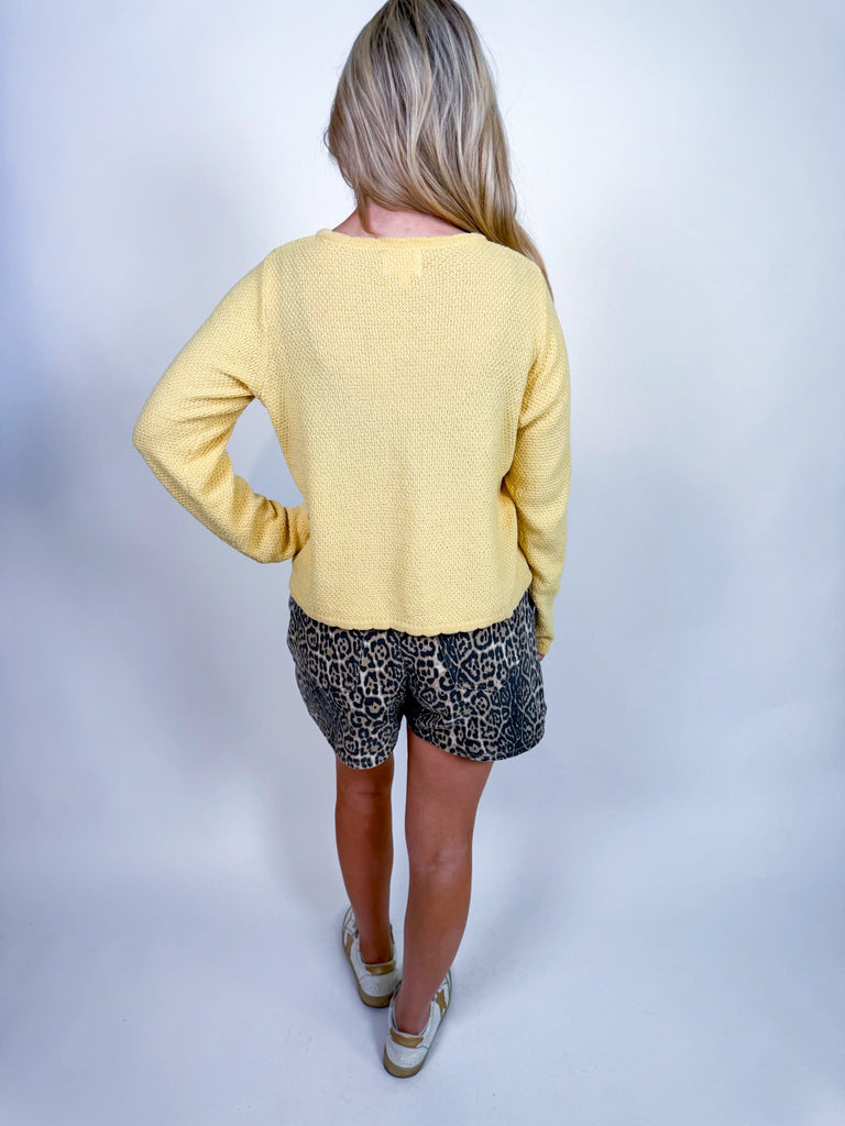 Woman wearing textured knit button-front cardigan in butter yellow and cornflower blue