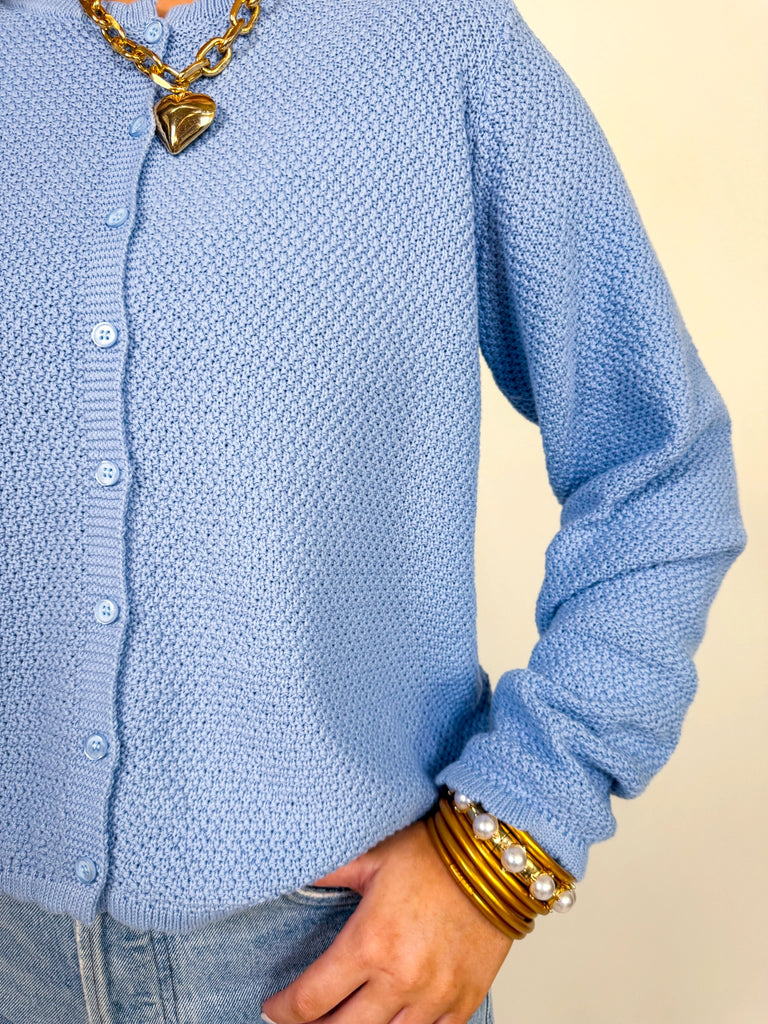 Woman wearing textured knit button-front cardigan in butter yellow and cornflower blue