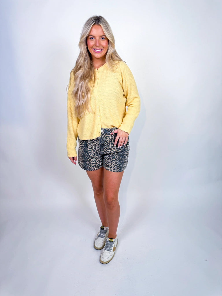 Woman wearing textured knit button-front cardigan in butter yellow and cornflower blue