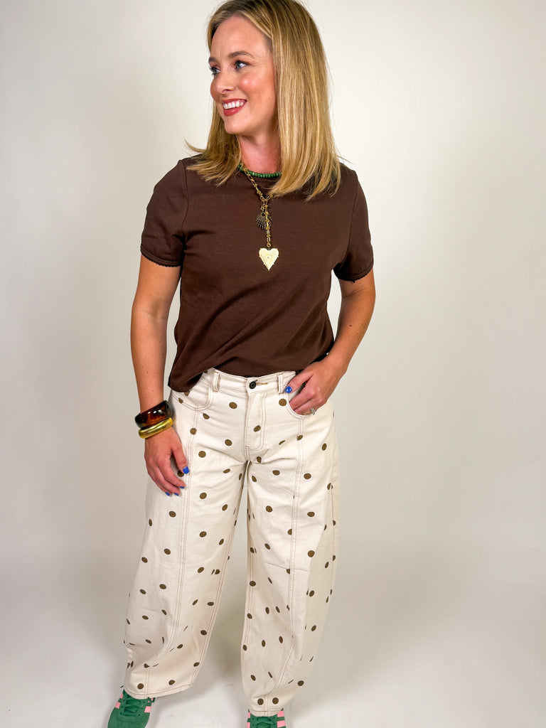 Woman wearing a cocoa brown short sleeve crew neck tee with scalloped hem detail