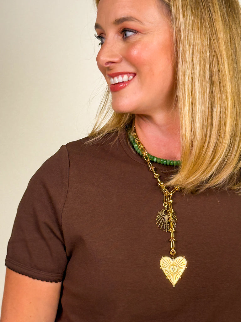 Woman wearing a cocoa brown short sleeve crew neck tee with scalloped hem detail