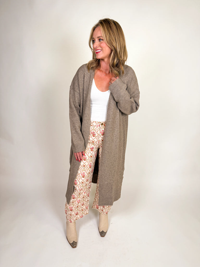 Woman wearing a longline taupe cardigan sweater with open front design