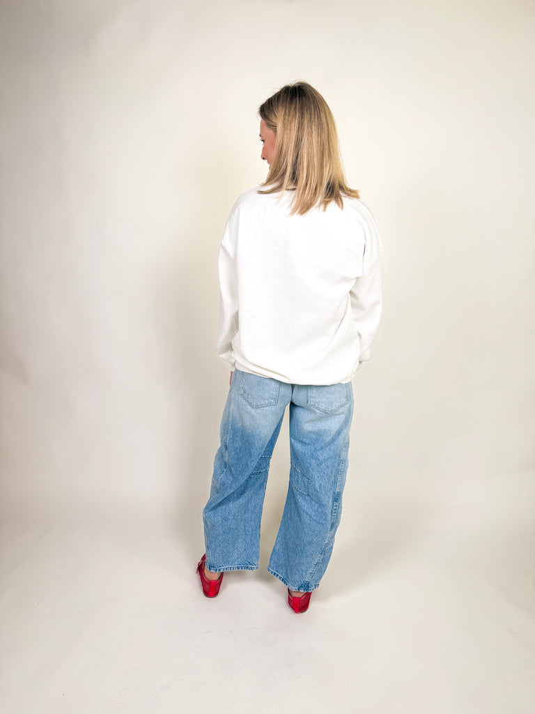 Woman wearing a white oversized sweatshirt with “i need a diet coke.