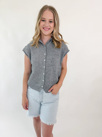 Woman wearing a sleeveless gray knit button-up top