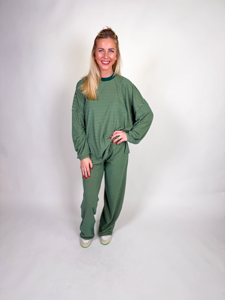 Woman wearing a green striped loungewear set with oversized long-sleeve top and wide-leg pants