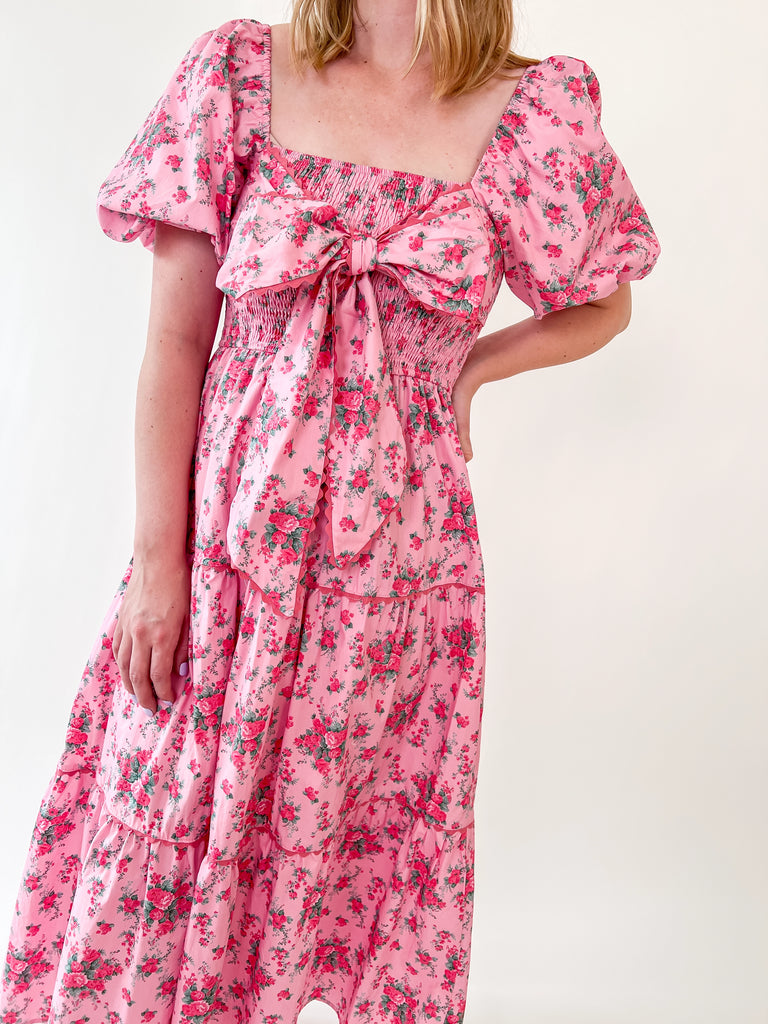 Pink floral dress with bow front, puff sleeves, and smocked top