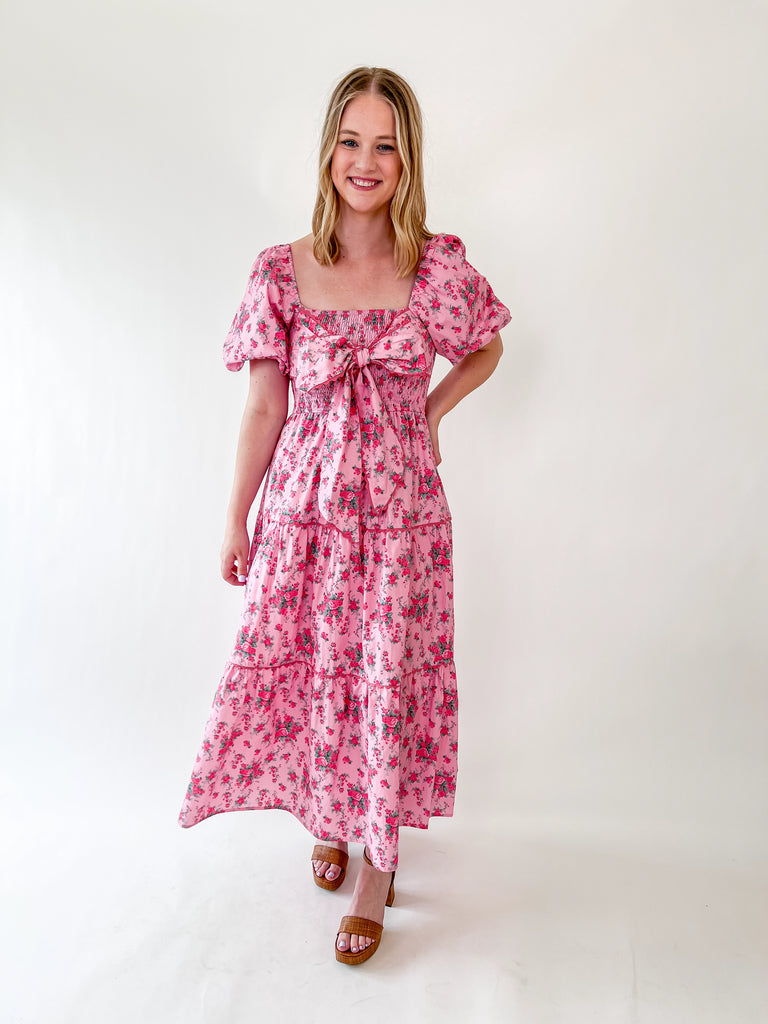 Pink floral dress with bow front, puff sleeves, and smocked top