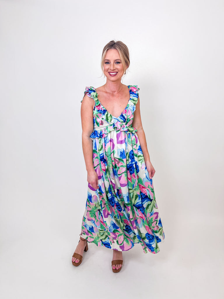 Woman wearing a floral ruffle maxi dress with an open back and self-tie bow.