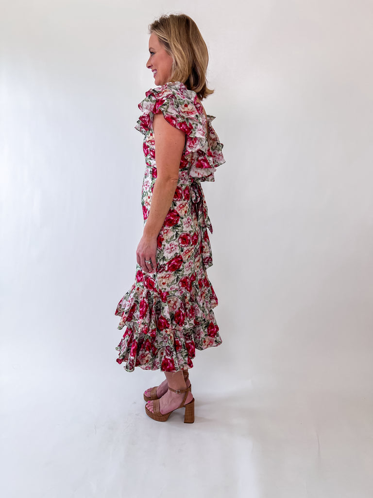Woman wearing a floral ruffle midi dress with an open back and self-tie bow.