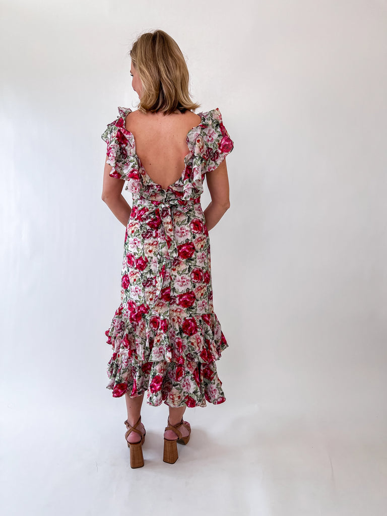 Woman wearing a floral ruffle midi dress with an open back and self-tie bow.