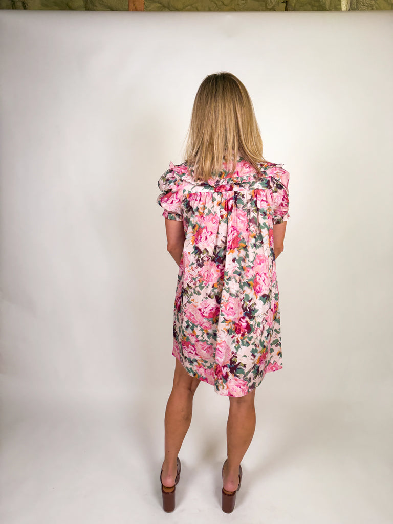 Woman wearing a floral pink mini dress with ruffle neckline and short sleeves