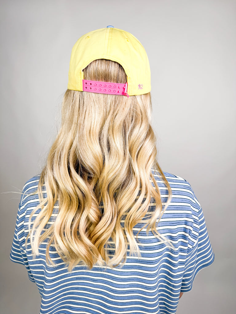model wearing Grateful Baseball Cap with yellow front, blue embroidered text, cheetah print bill, and pink snapback