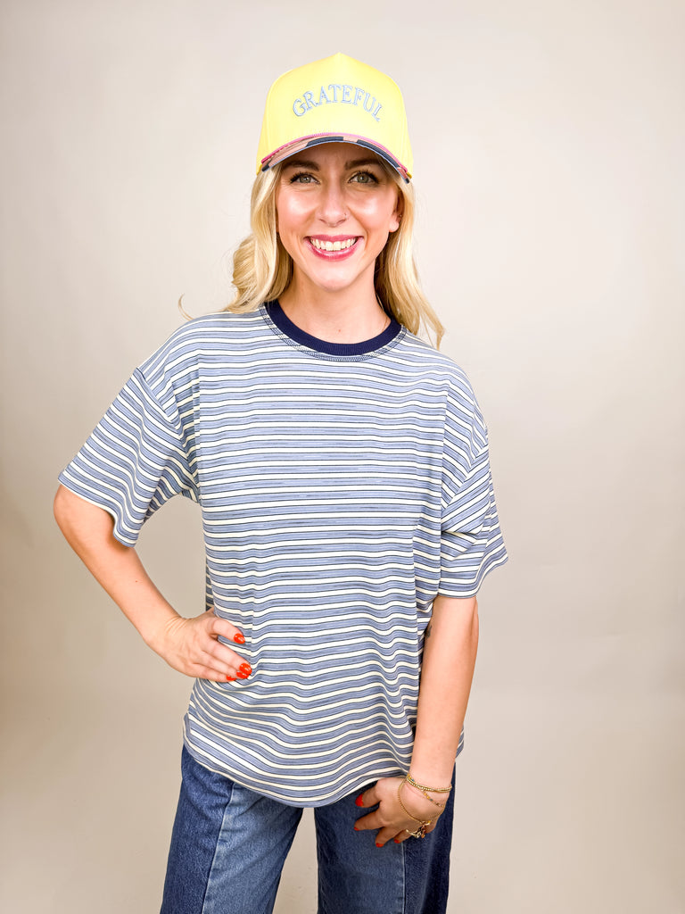 model wearing Grateful Baseball Cap with yellow front, blue embroidered text, cheetah print bill, and pink snapback