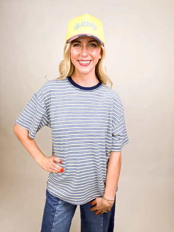 model wearing Grateful Baseball Cap with yellow front, blue embroidered text, cheetah print bill, and pink snapback