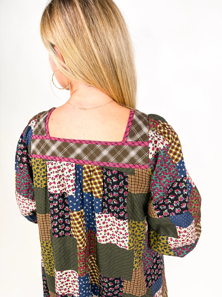 model wearing long sleeve patchwork babydoll dress in earthy floral tones